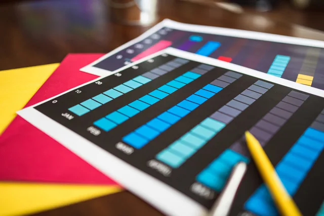 Close-up of colorful financial charts and a pencil on a wooden desk. Landing page software metrics: define the event, population and denominator for each