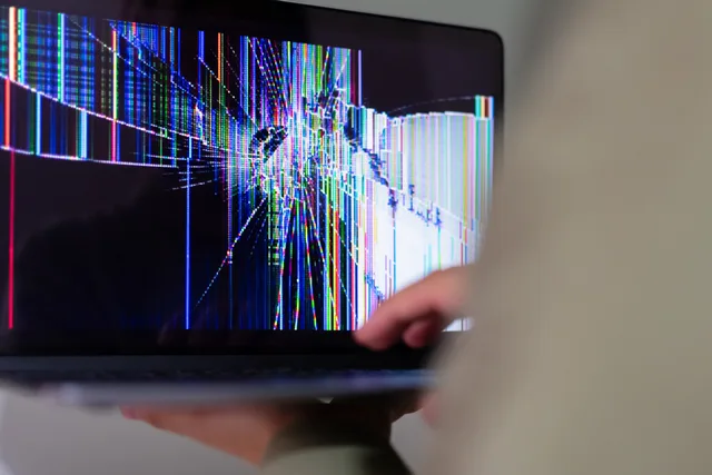A close-up view of a cracked laptop screen displaying colorful digital distortion. Five landing page software risks, from an unsupported AI claim to a supplier change