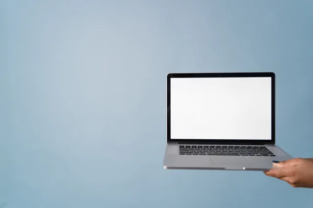 A person holding a laptop with a blank screen against a blue background, perfect for mockups. How to Create a Sales Funnel for a UK Service Business